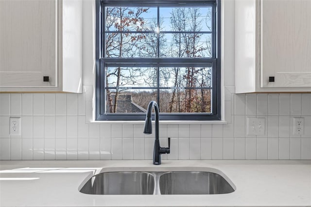 kitchen with backsplash, light countertops, and a sink