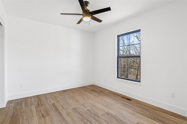 unfurnished room with a healthy amount of sunlight, visible vents, baseboards, and wood finished floors