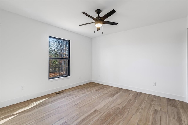 unfurnished room with a ceiling fan, visible vents, baseboards, and wood finished floors