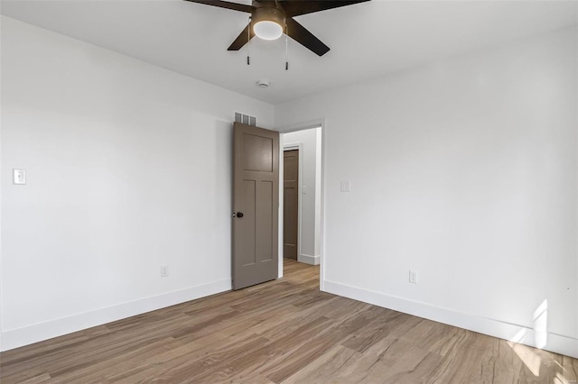 spare room featuring a ceiling fan, light wood-type flooring, visible vents, and baseboards