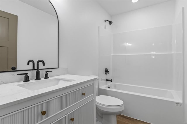 bathroom featuring wood finished floors, vanity, toilet, and shower / bathtub combination