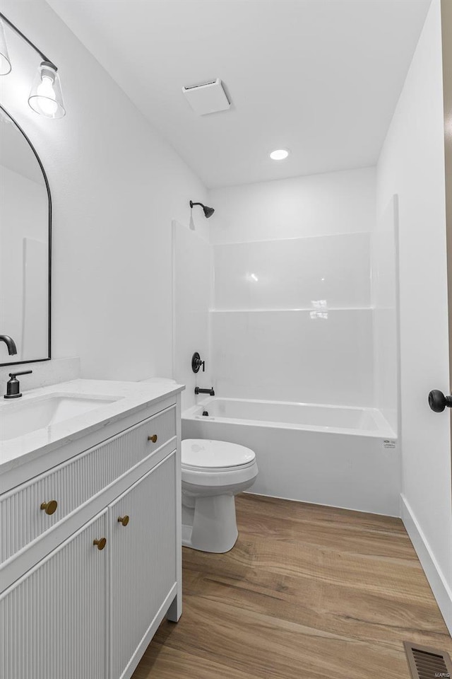 bathroom featuring visible vents, toilet, shower / bathtub combination, wood finished floors, and vanity