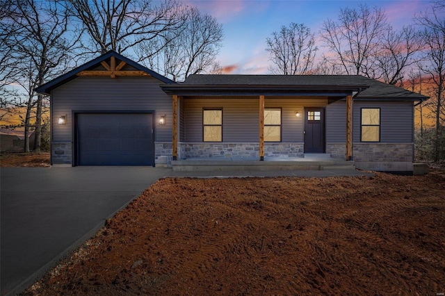 view of front facade featuring an attached garage, stone siding, driveway, and a porch