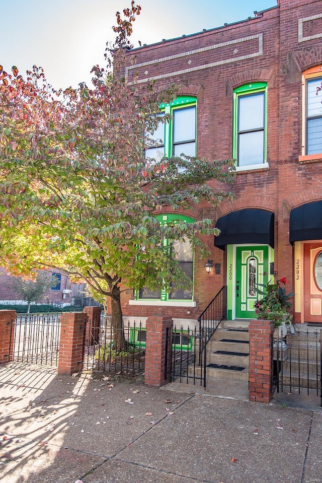 multi unit property featuring a fenced front yard, a gate, and brick siding