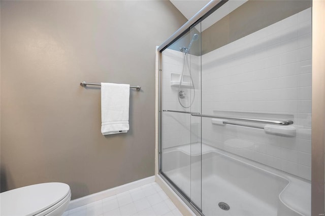 bathroom with toilet, a stall shower, and baseboards