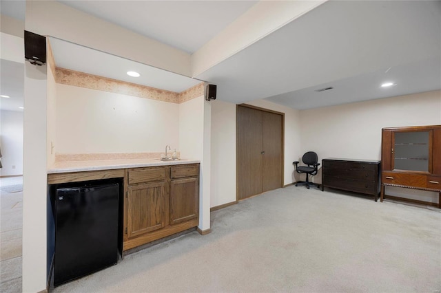 bar with refrigerator, indoor wet bar, visible vents, light carpet, and a sink