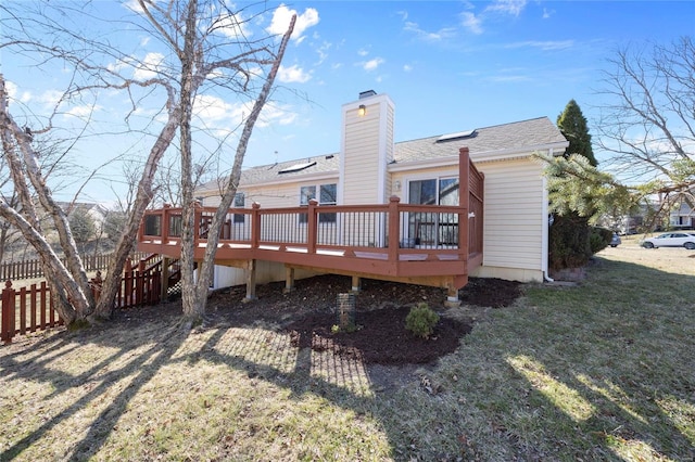 back of property with a yard, fence, a chimney, and a wooden deck