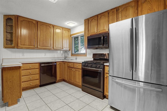 kitchen with light countertops, stainless steel appliances, brown cabinets, and a sink