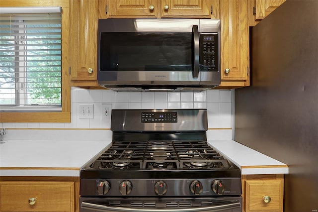 kitchen featuring light countertops, decorative backsplash, stainless steel appliances, and brown cabinets