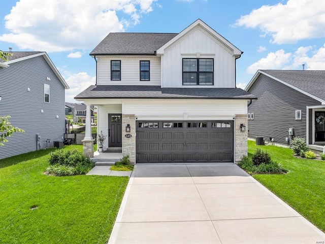 view of front of home with an attached garage, driveway, stone siding, board and batten siding, and a front yard