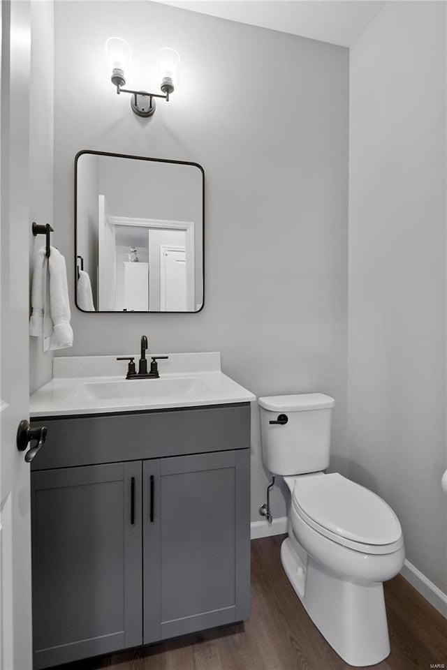 bathroom with baseboards, vanity, toilet, and wood finished floors