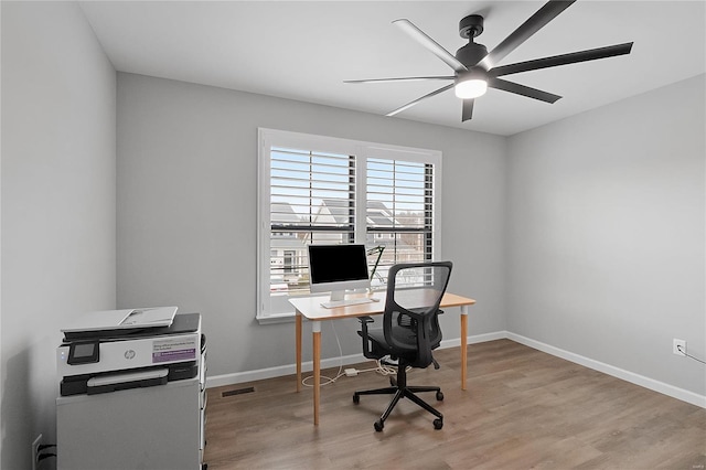 home office featuring a ceiling fan, visible vents, baseboards, and wood finished floors