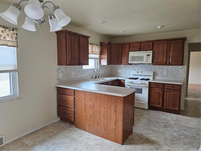 kitchen with white appliances, visible vents, a peninsula, light countertops, and a sink