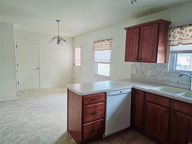 kitchen featuring decorative light fixtures, light countertops, a sink, dishwasher, and a peninsula