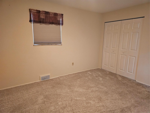 unfurnished bedroom featuring a closet, visible vents, and carpet flooring