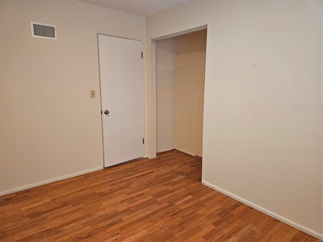 empty room featuring light wood-type flooring, visible vents, and baseboards