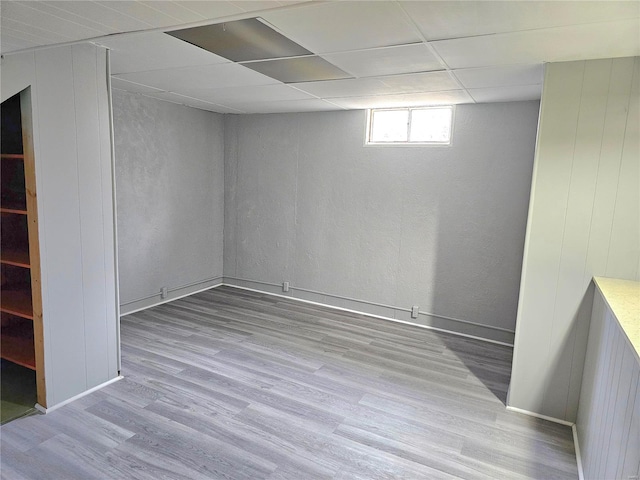 below grade area featuring a paneled ceiling and light wood-style flooring