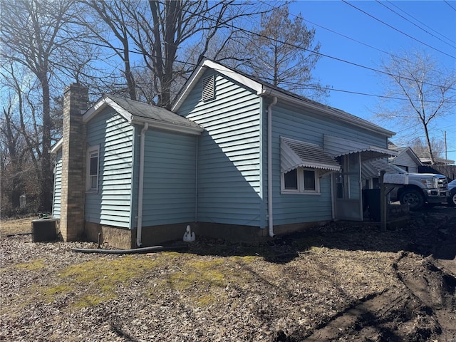 view of home's exterior featuring a chimney and central AC