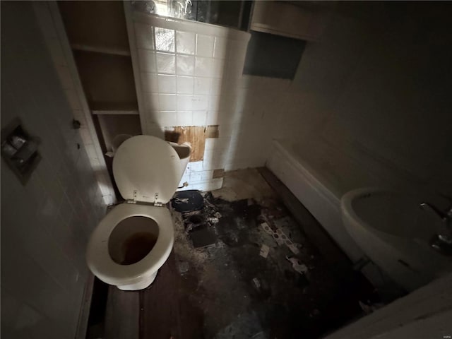 bathroom with toilet and tile walls