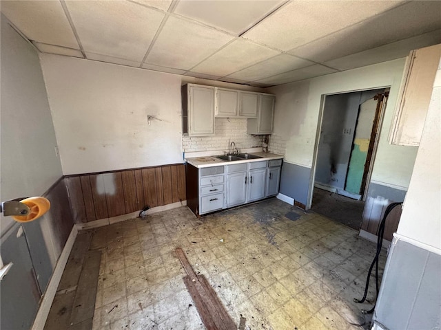 kitchen featuring a wainscoted wall, light countertops, light floors, and a sink