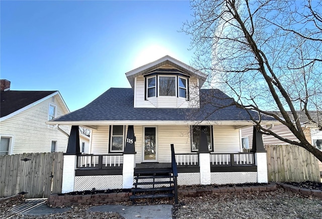 bungalow-style house featuring a porch, a shingled roof, and fence