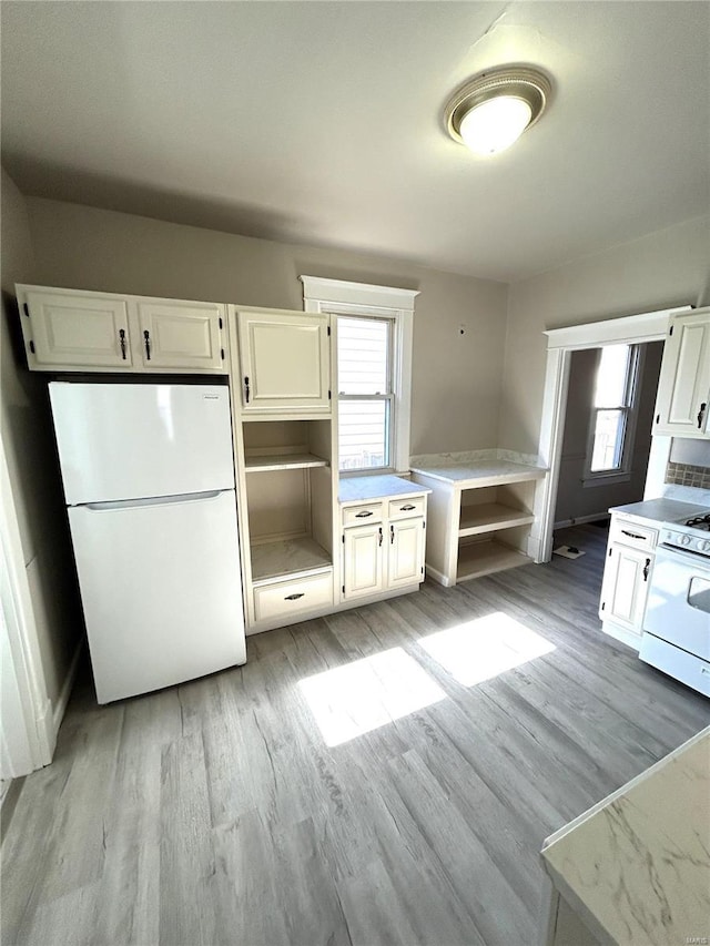 kitchen with light wood-type flooring, a wealth of natural light, and white appliances