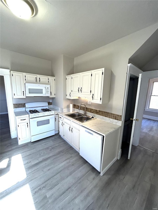 kitchen featuring white appliances, light countertops, light wood-style floors, white cabinetry, and a sink