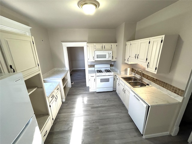 kitchen with white appliances, dark wood-style flooring, a sink, white cabinets, and light countertops