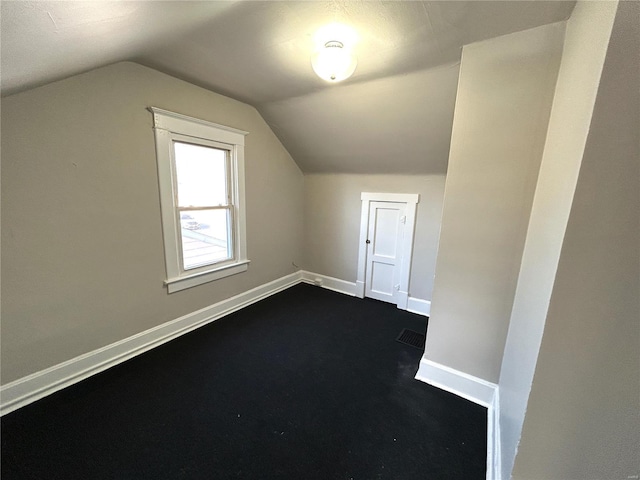 additional living space featuring lofted ceiling, visible vents, and baseboards