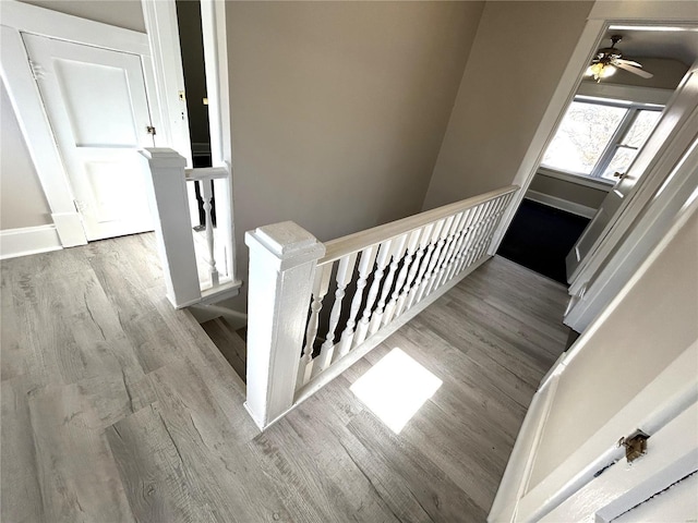 staircase with ceiling fan, wood finished floors, and baseboards