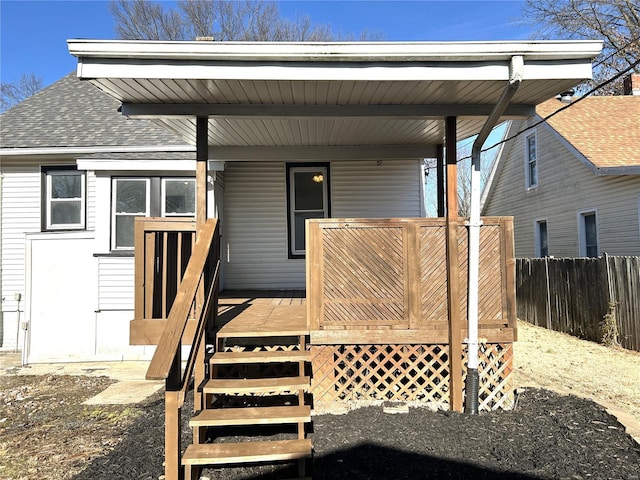 doorway to property featuring roof with shingles and fence