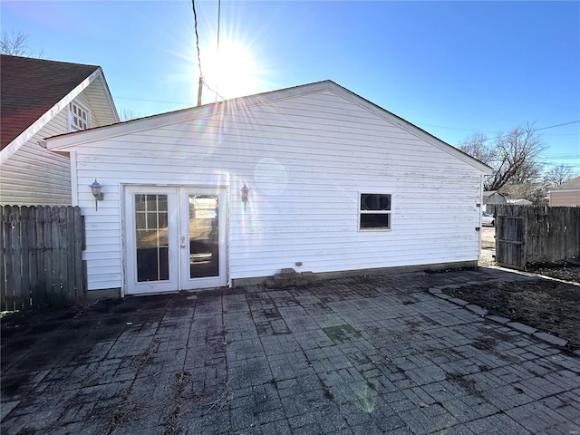 rear view of house with fence, a patio, and french doors