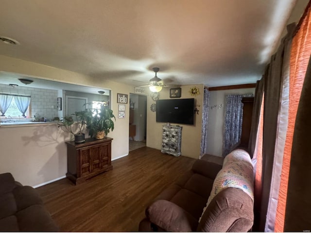 living room with visible vents, dark wood-type flooring, and a ceiling fan