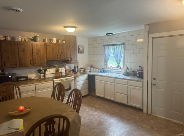 kitchen with electric range, a sink, white cabinetry, light countertops, and decorative backsplash