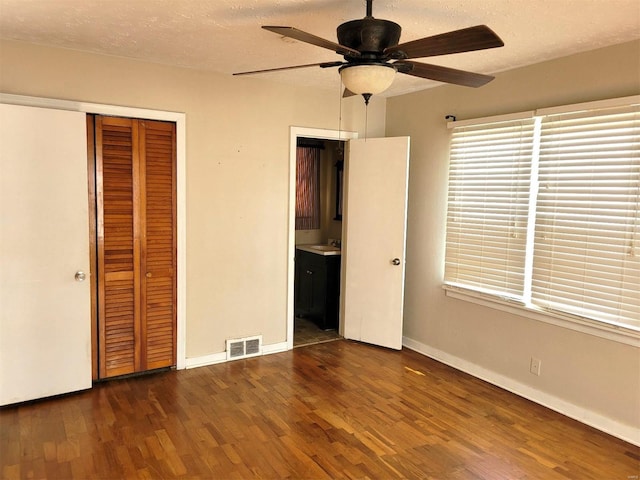 unfurnished bedroom featuring a sink, a closet, visible vents, and wood finished floors