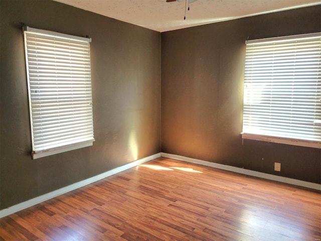 empty room featuring a ceiling fan, baseboards, and wood finished floors