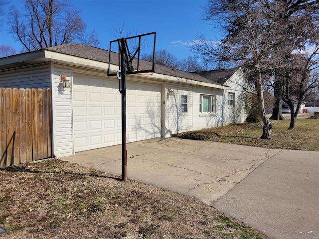 view of property exterior featuring concrete driveway, fence, and an attached garage