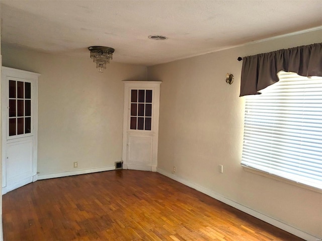 unfurnished room with baseboards, a wealth of natural light, and wood finished floors