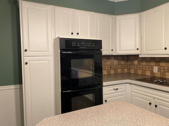 kitchen with decorative backsplash, white cabinets, and black appliances