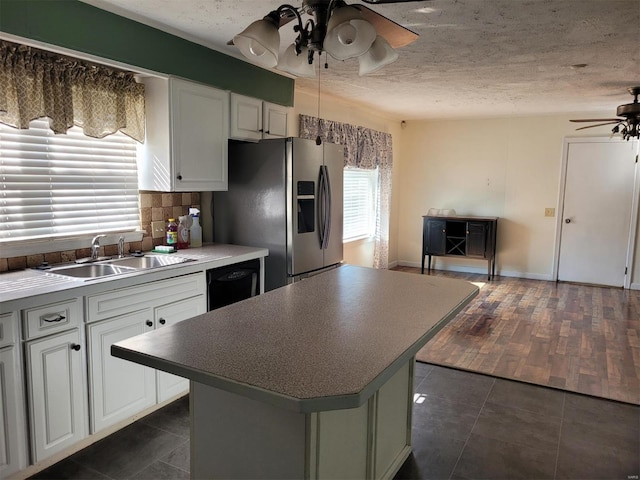 kitchen with a sink, a ceiling fan, dishwasher, tasteful backsplash, and stainless steel fridge