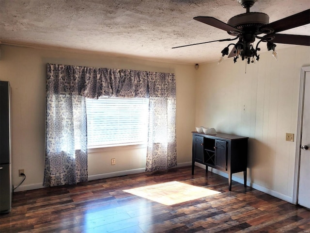 interior space featuring ceiling fan, a textured ceiling, baseboards, and wood finished floors