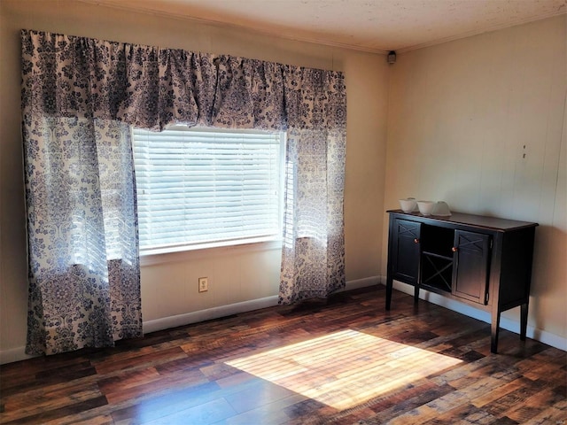 interior space featuring crown molding, baseboards, and wood finished floors