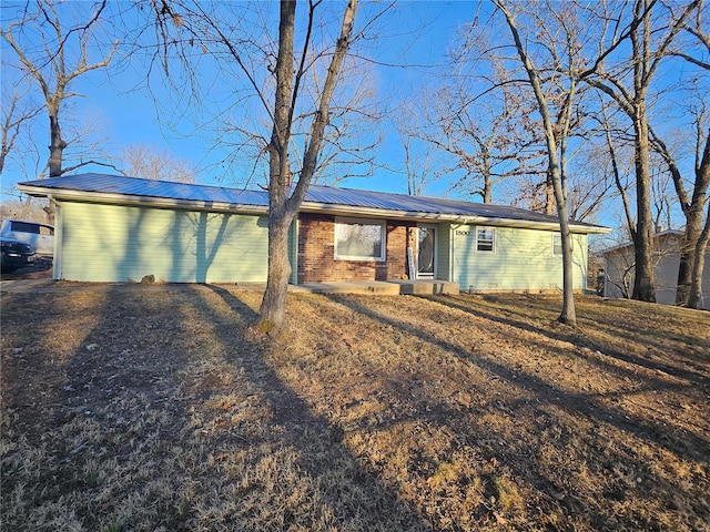 single story home featuring metal roof and brick siding