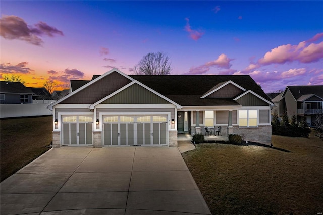 craftsman-style house with driveway, stone siding, and an attached garage