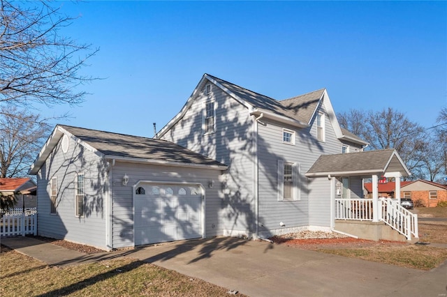 view of side of home featuring a garage, covered porch, and concrete driveway