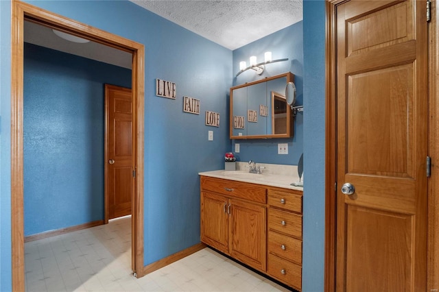 bathroom with a textured ceiling, baseboards, vanity, and tile patterned floors