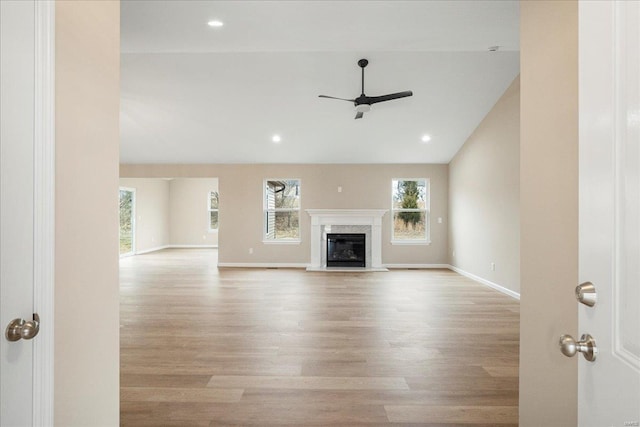 unfurnished living room featuring a fireplace, wood finished floors, a ceiling fan, and baseboards