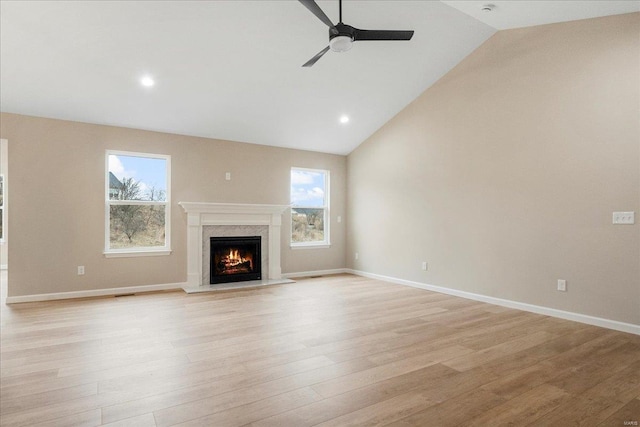 unfurnished living room featuring light wood-type flooring, plenty of natural light, baseboards, and ceiling fan