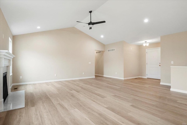 unfurnished living room with a fireplace with raised hearth, ceiling fan, light wood-style flooring, visible vents, and vaulted ceiling