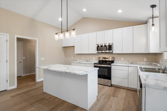 kitchen with vaulted ceiling, stainless steel appliances, light wood-type flooring, white cabinetry, and a sink